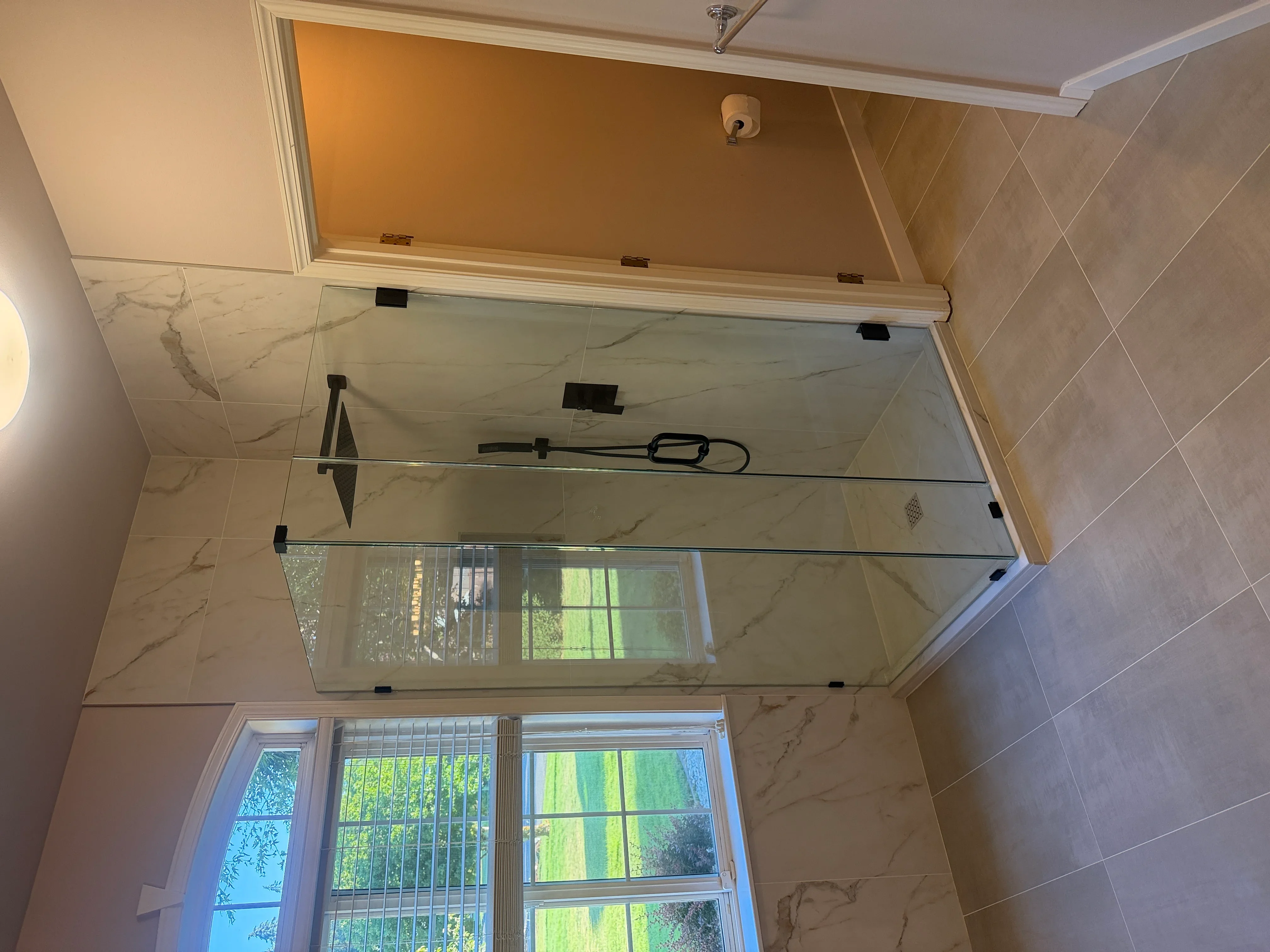Marble tile bathroom with frameless glass shower enclosure and recessed lighting