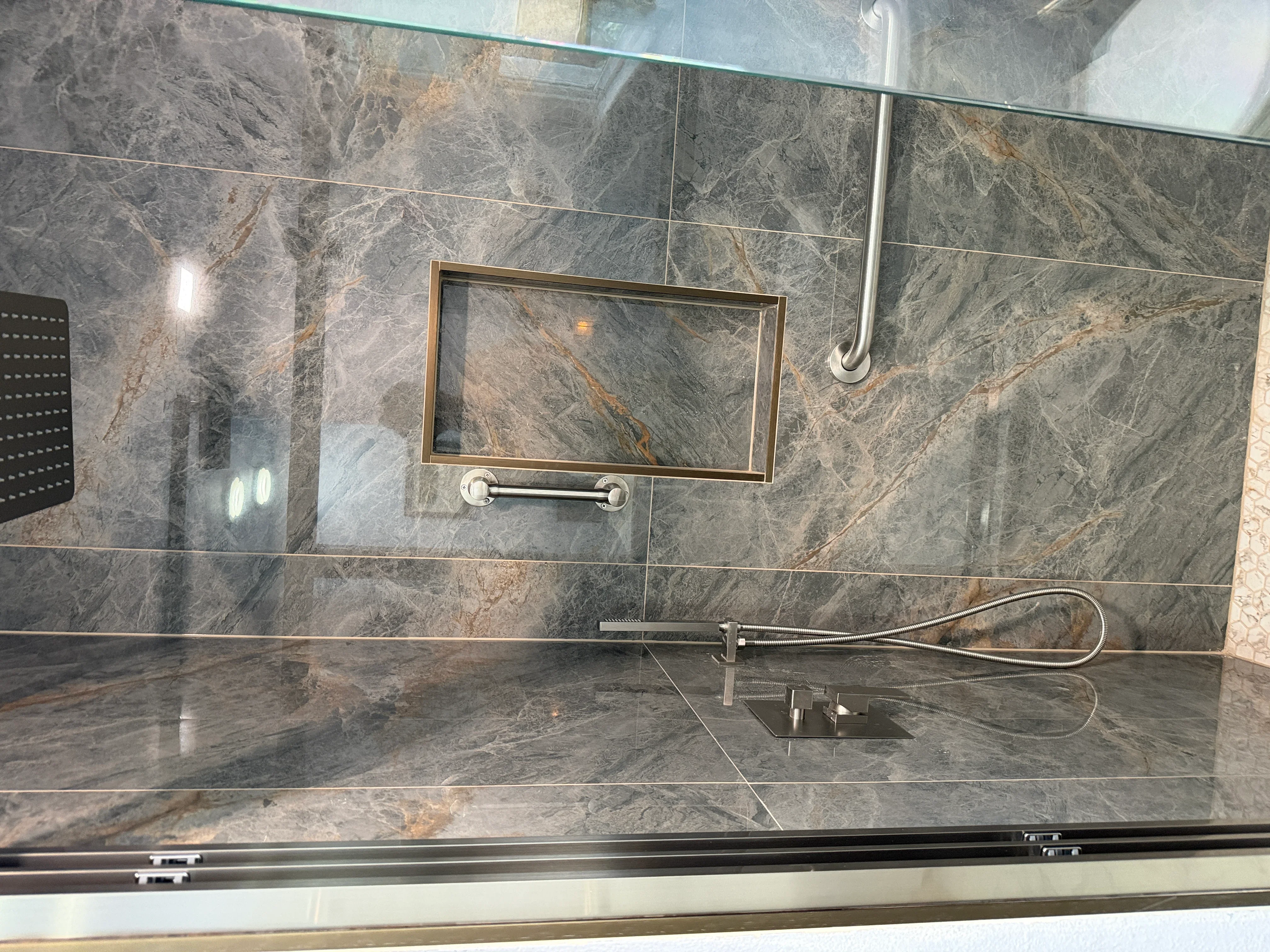 Gray marble tile shower with frameless glass doors and brushed nickel fixtures