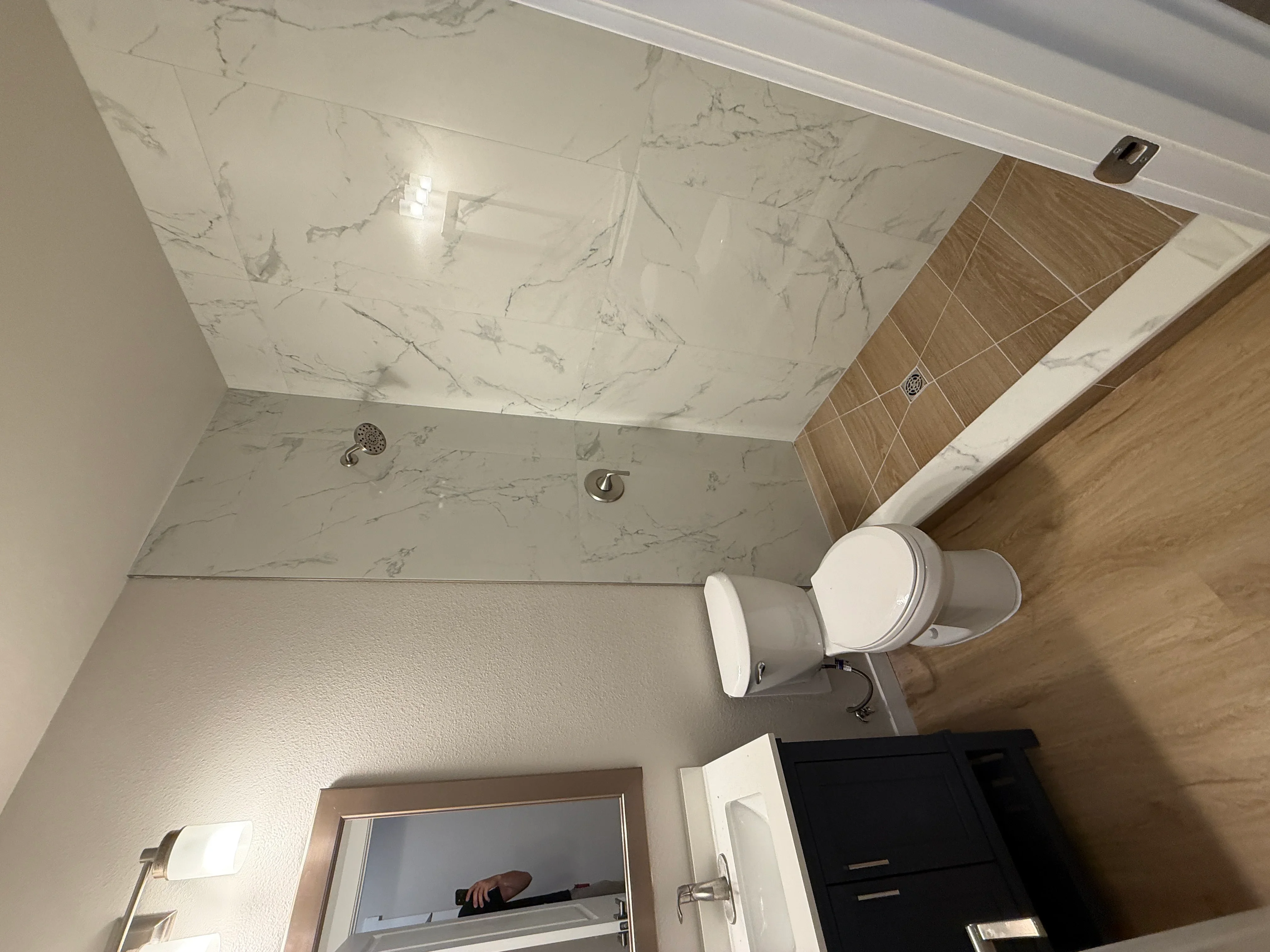 Marble tile shower enclosure with wood-grain accent tiles and chrome fixtures