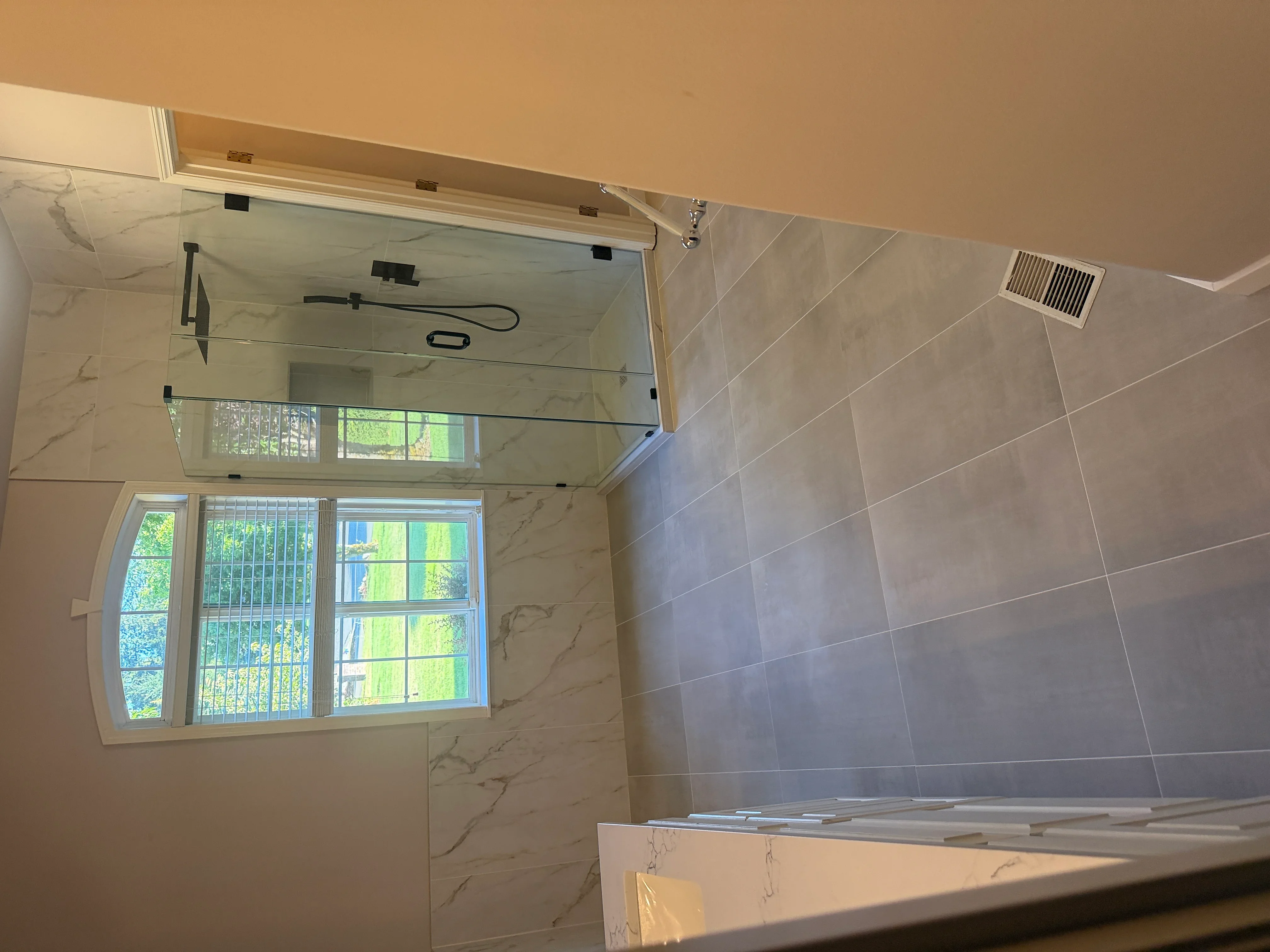 Marble tile bathroom with frameless glass shower enclosure and diagonal wall tile pattern