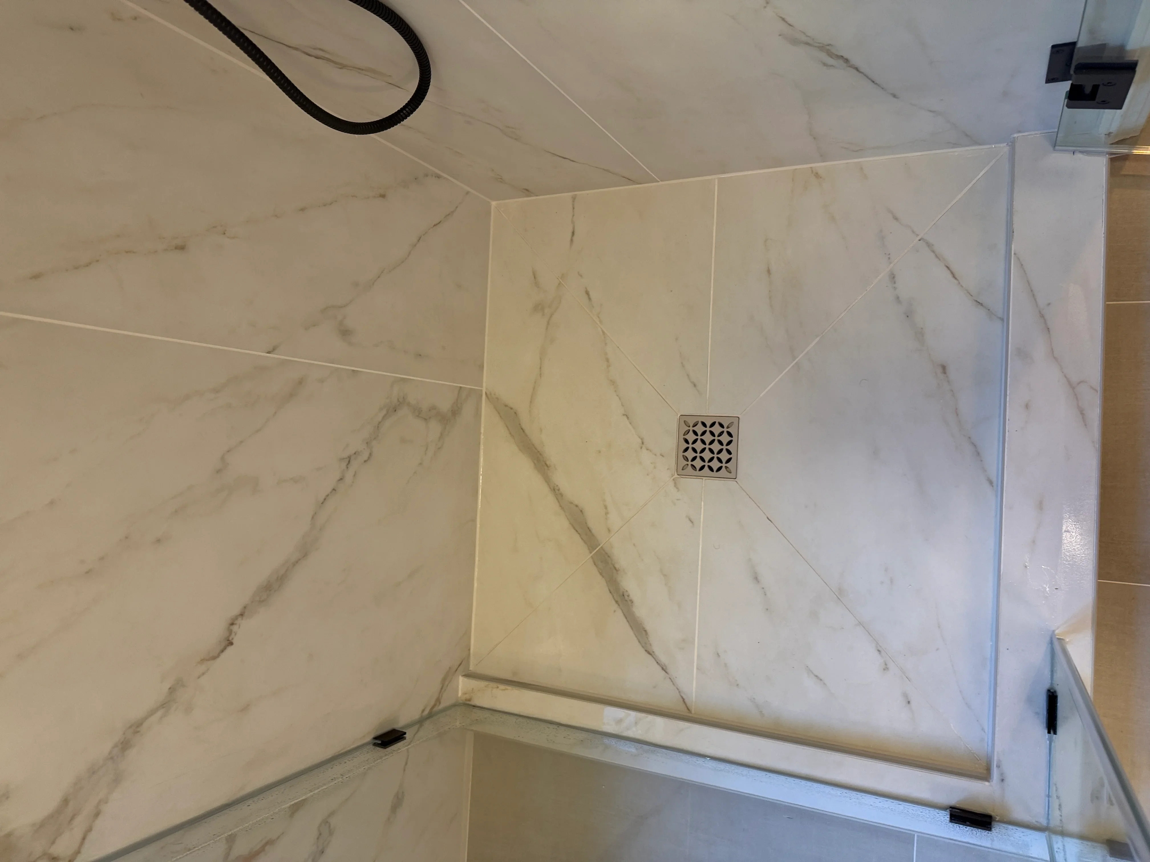 Marble-look porcelain tile shower walls and ceiling with integrated drain and chrome fixture