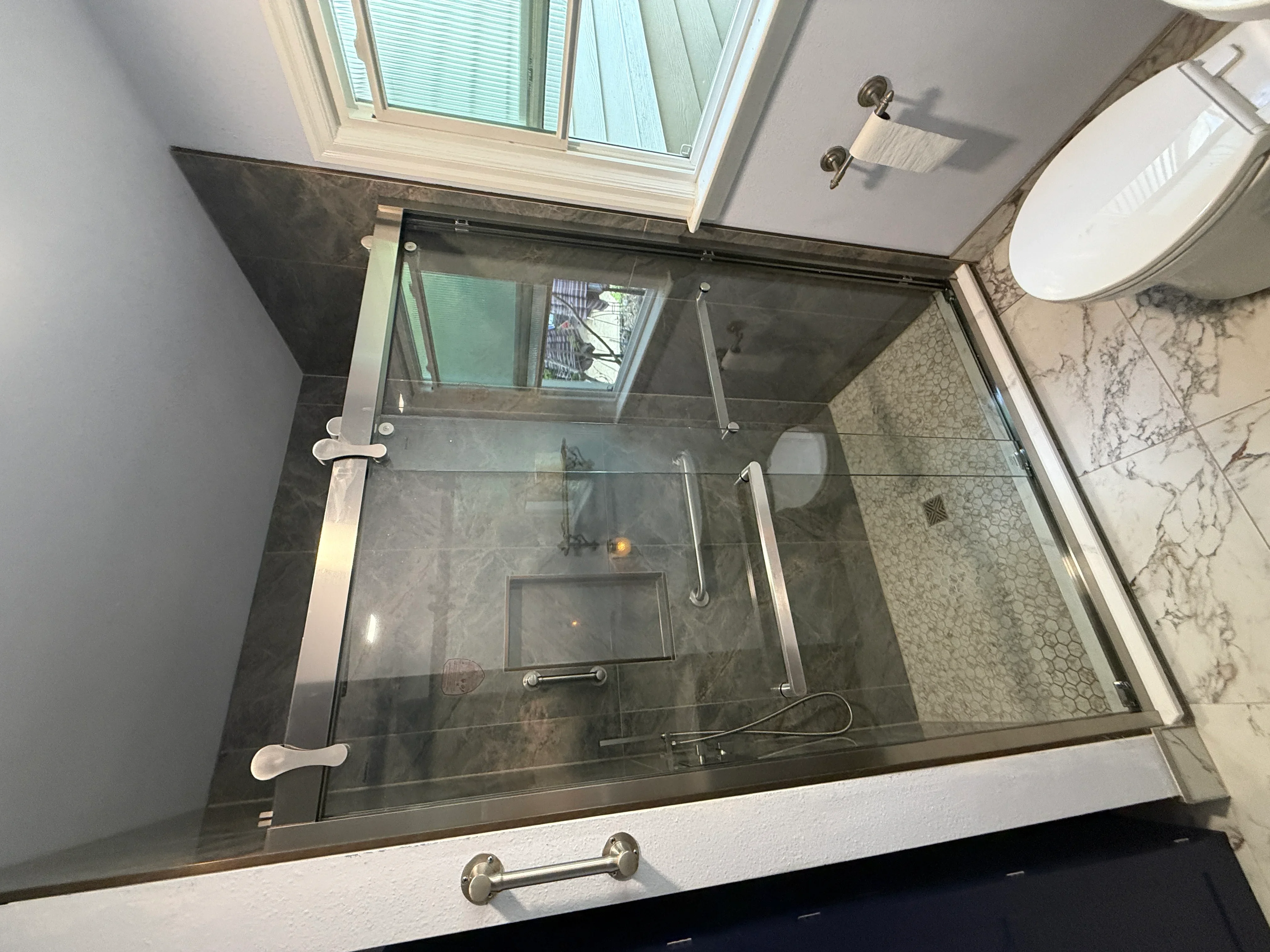 Frameless glass shower enclosure with dark gray tile walls and chrome hardware in modern bathroom