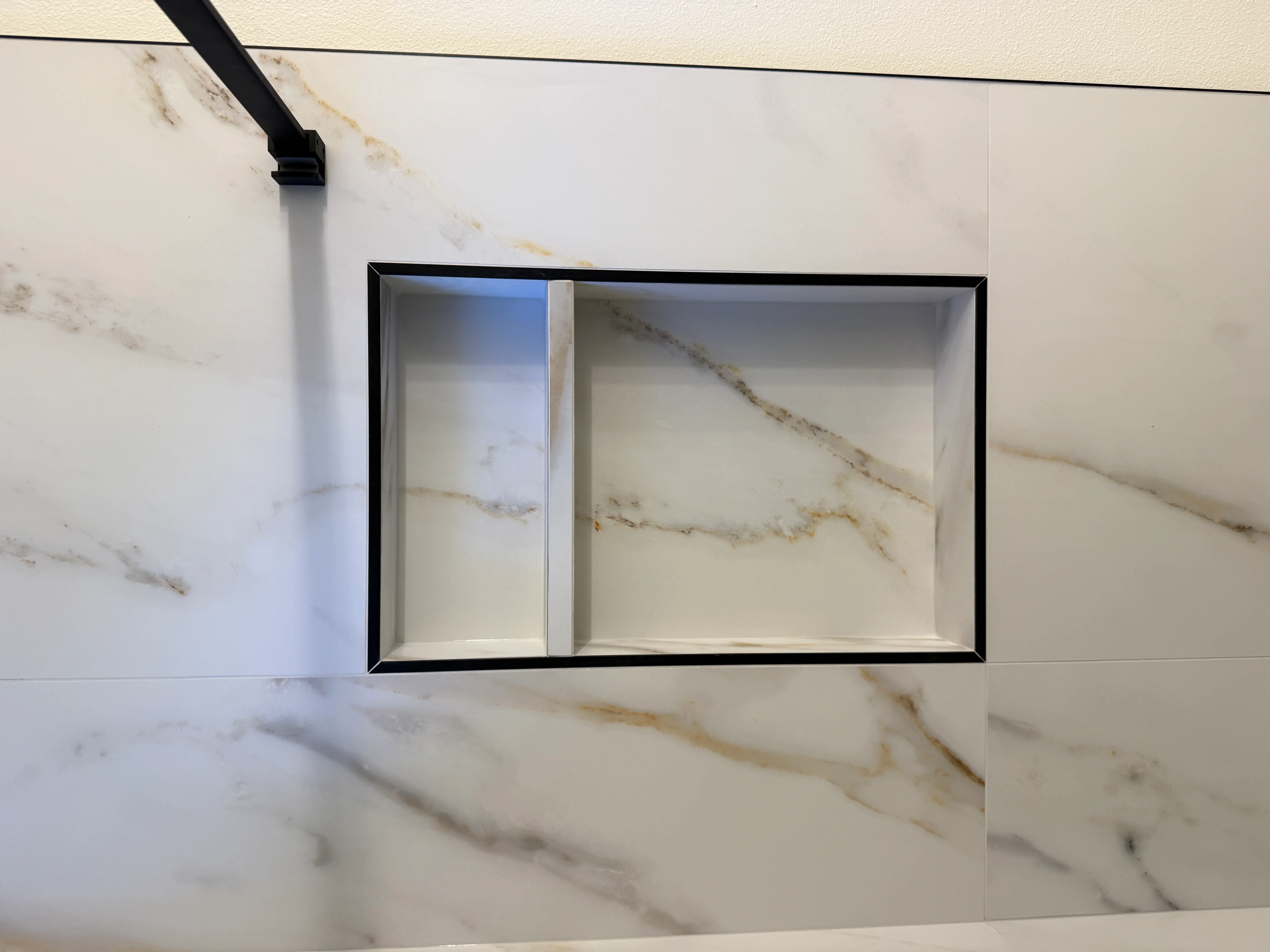 Marble tile bathroom wall with black-framed recessed medicine cabinet and mirrored doors